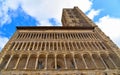 Detail of facade with columns, windows and bell tower of medieval Basilica of Santa Maria della Pieve church against cloudy blue s