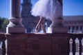 Detail of feet in classical ballet slippers of a woman in a white tutu illuminated by a ray of sunlight between two columns Royalty Free Stock Photo