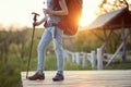 Detail of female backpacker finishing her hiking at sunset in nature, holding bottle of water and walking stick. healthy living,