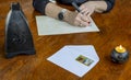 Detail of female hands about to write a letter with pen and paper on an old wooden table with burning candle and black lantern Royalty Free Stock Photo