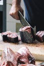 Detail of a fisherman cutting tuna with a huge cleaver on a wooden board. Blurred tuna meat in the foreground. Traditional fish