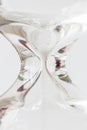 Detail of flowing white sand crystal in hourglass on white background, time concept.