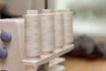 Detail of four thread spools with white thread on overlock sewing machine