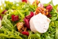 Detail of fresh arugula salad with beetroot, goat cheese and walnuts on glass plate on white background, product photogra