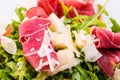 Detail of fresh arugula vegetable salad with ham and cheese on glass plate on white background, product photography for r