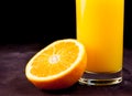 Detail of full glass of orange juice near half orange Royalty Free Stock Photo