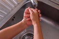 Detail of a girl`s hands. Rinsing her hands in the kitchen sink. Washing her hands. Concept of cleaning