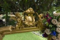 Detail of golden angels of an antique mirror adorned with roses in the middle of the garden with a background of out of focus