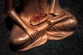 Detail of golden Buddha statue holding flower leaves in the hand