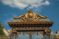 Detail of golden iron gate and fence lavishly decorated under sunny blue sky in Paris. Royalty Free Stock Photo