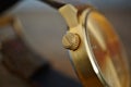 Detail of a golden watch with indented gold-plated crown as a symbol of time or exactness