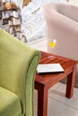 Detail of green armchair with table, book and cokctail