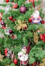 Detail of green Christmas (Chrismas) tree with colored ornaments, globes, stars, Santa Claus, Snowman Royalty Free Stock Photo