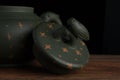 Detail of green traditional chinese Yixin clay teapot with cicada on the cover. On the wooden table and black backround Royalty Free Stock Photo