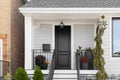 A detail of a grey and white home with a black front door and railing.