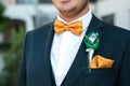 Detail of a groom`s dark blue costume and an orange bow tie Royalty Free Stock Photo