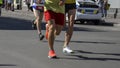 Detail of a group of runners during a city marathon. Legs and sneakers. Muscles under stress