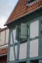 Detail of a half-timbered house wall with window, iron fittings and half-opened shutters in white, green and grey. Royalty Free Stock Photo