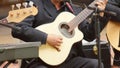 Detail of the hand of an artist dressed in black playing the strings of an acoustic guitar