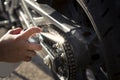 Detail of the hand of a biker woman cleaning and oiling the chain of the motorcycle. Motorcycle care and maintenance concept