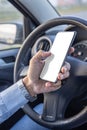 Detail of the hand of a driver holding a mobile phone with a blank screen on the steering wheel of the car Royalty Free Stock Photo