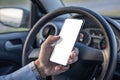 Detail of the hand of a driver holding a mobile phone with a blank screen on the steering wheel of the car Royalty Free Stock Photo