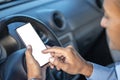 Detail of the hand of a driver holding a mobile phone with a blank screen on the steering wheel of the car with copy space Royalty Free Stock Photo