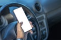 Detail of the hand of a driver holding a mobile phone with a blank screen on the steering wheel of the car with copy space Royalty Free Stock Photo