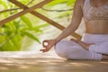 Detail of hand of fit and relaxed woman doing yoga and meditation exercise sitting in lotus position outdoors at bamboo hut