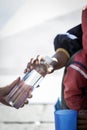 Detail of hand giving a water bottle to a homeless Royalty Free Stock Photo