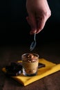 Detail of a hand holding a teaspoon ready to have the dalgona coffee cream dessert. On dark background Royalty Free Stock Photo