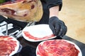 Detail of the hand of a professional Iberian ham cutter placing the slices on a plate. Concept pork, food, ham, iberian, spain,