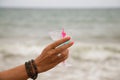 Detail of hand raising glass in the air with a blue drink. In the background you can see the sky and the sea in the horizon