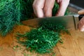 Detail of hands chopping up a bunch of dill on wood chopping boa Royalty Free Stock Photo