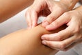 Detail of hands doing osteopathic massage on female calf muscle.