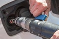 Detail of the hands holding the hose while refueling in the eco-car