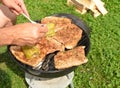 Detail of the hands of a man grilling meat and peppers