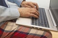 Detail of the hands of a man using the keyboard of a laptop and a dress with a shirt, tie and pajama pants