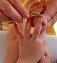 Square photograph of the detail of a woman`s hands cutting a child nails