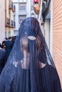 Detail of the head of a woman with a black spanish mantilla and peineta ornamental comb, seen from behind, in a Holy Week