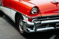 Detail of the headlight or left front light and part of the side of a red and white vintage car from the 50s. Mobility concept