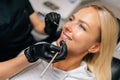 Detail headshot of happy blonde female patient having treatment in dentistry clinic. Close-up hands of unrecognizable Royalty Free Stock Photo