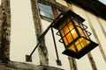 Historical old lit street lamp hanging from a building. Royalty Free Stock Photo