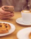 Detail image of unrecognisable man drinking coffee and holding smart phone while having breakfast in restaurant. Royalty Free Stock Photo