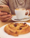 Detail image of unrecognisable man drinking coffee and holding smart phone while having breakfast in restaurant. Royalty Free Stock Photo