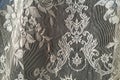 Detail of intricate patterns in an antique lace curtain hanging in a window Royalty Free Stock Photo