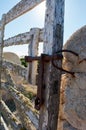 detail of iron latch on typical wooden door with lichens on stone wall next to the path with beautiful blue sky over