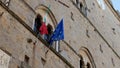 Detail on the Italian and European Union flags hanging on the facade of the ancient Palazzo dei Priori in the historic center of t Royalty Free Stock Photo