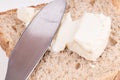 Detail of a knife spreading cheese on a bread slice on white background Royalty Free Stock Photo