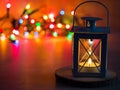 Detail of a lantern with tea candle and Christmas lights in background Royalty Free Stock Photo